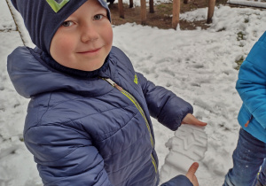 Chłopiec pokazuje odcisk buta w śniegu